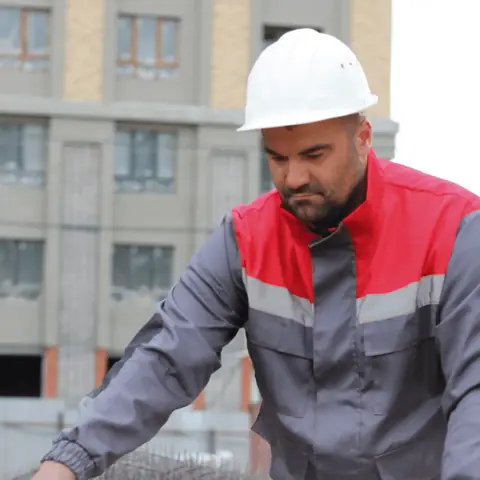 Рабочий в каске и спецодежде на стройплощадке